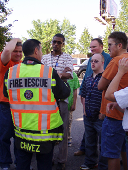 A fire rescue professional speaks with a group of people with disabilities