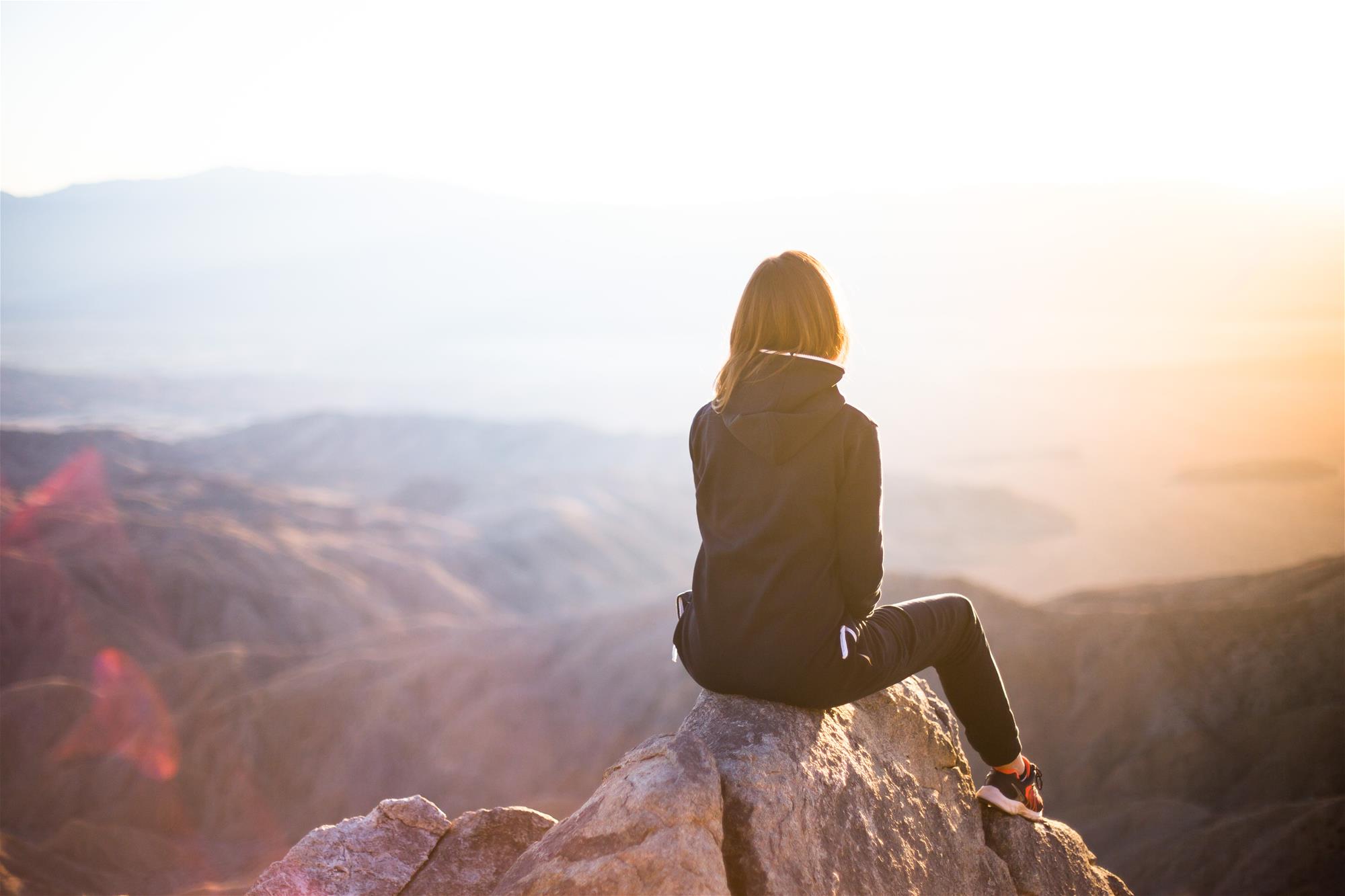 Woman sitting on top of a mountain looking at the landscape