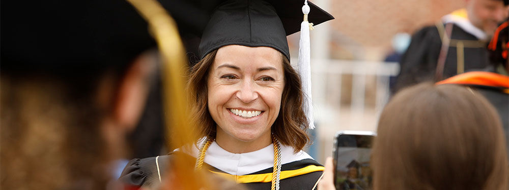 CU Denver graduate student smiling for the camera on commencement day