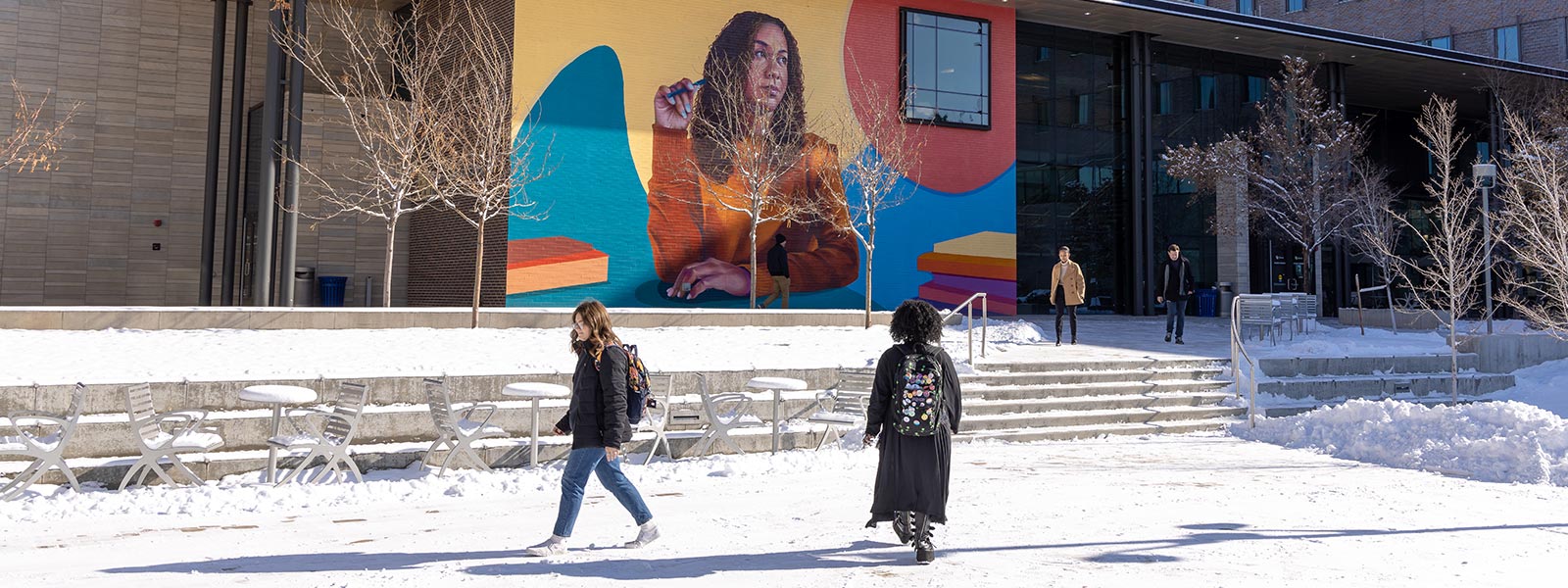CU Denver students walking on snowy campus with mural in background