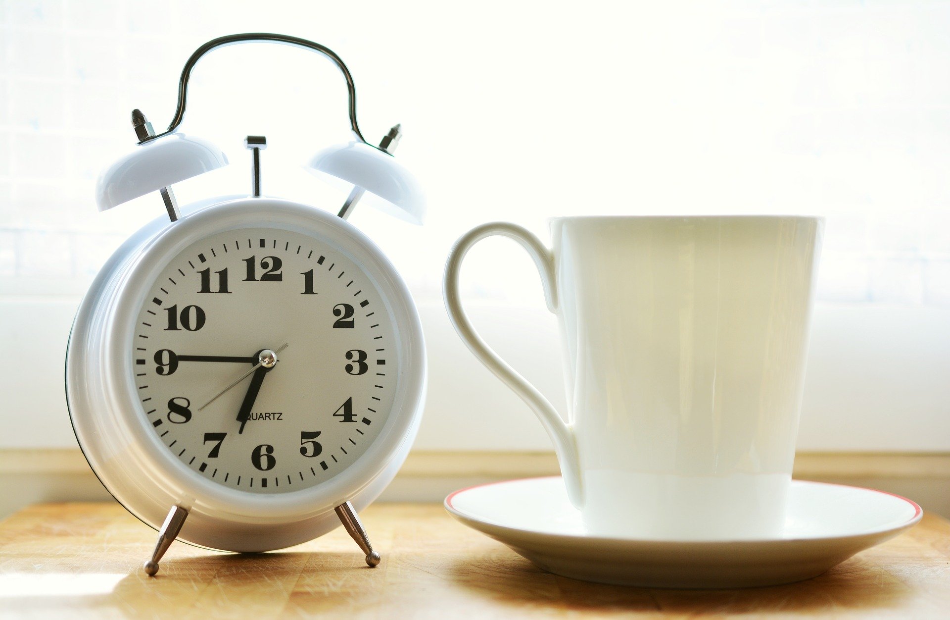 an alarm clock next to a cup of coffee