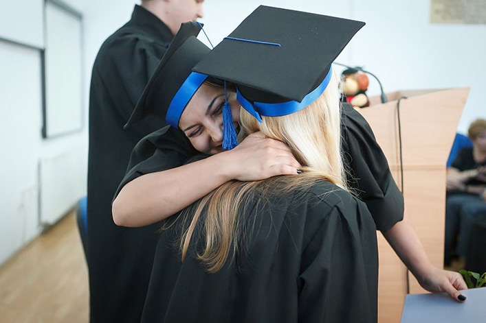 Two students embracing during a graduation ceremony