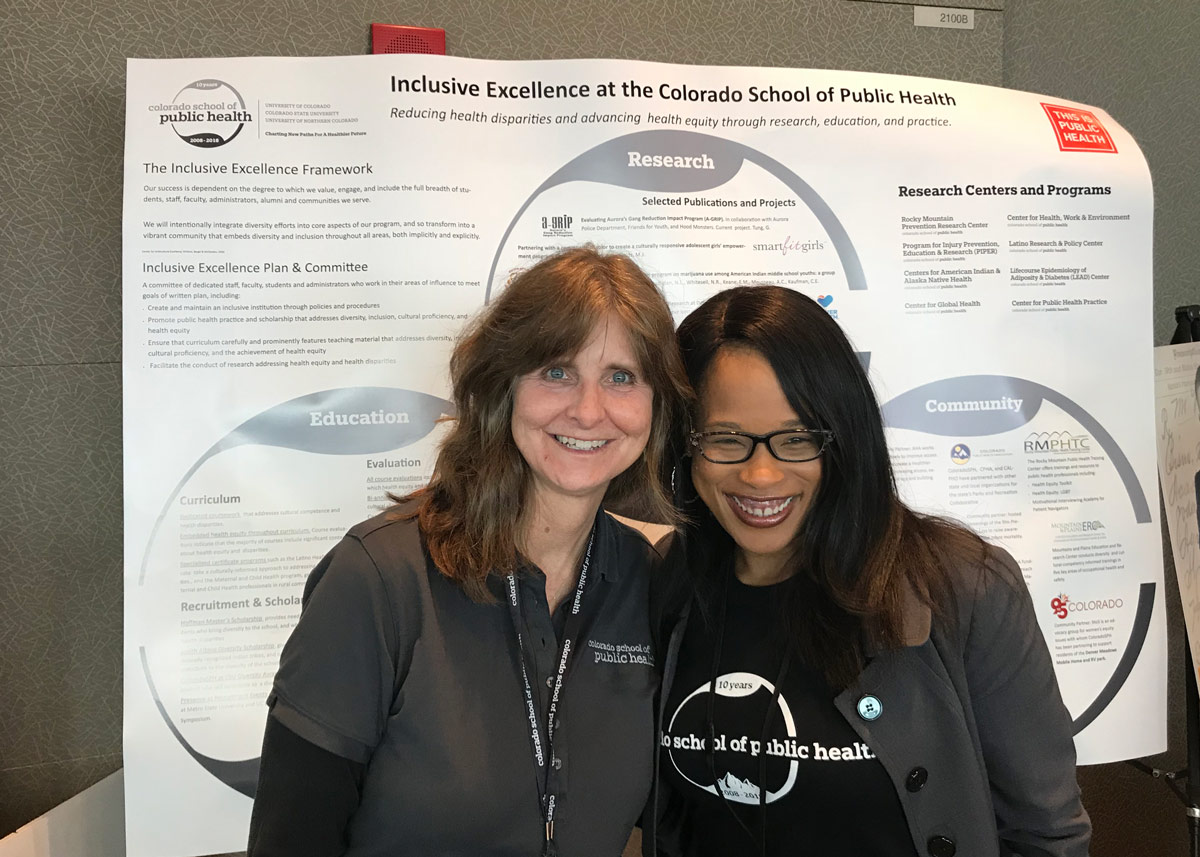 Lori Crane and Cerise Hunt in front of a research poster about inclusive excellence