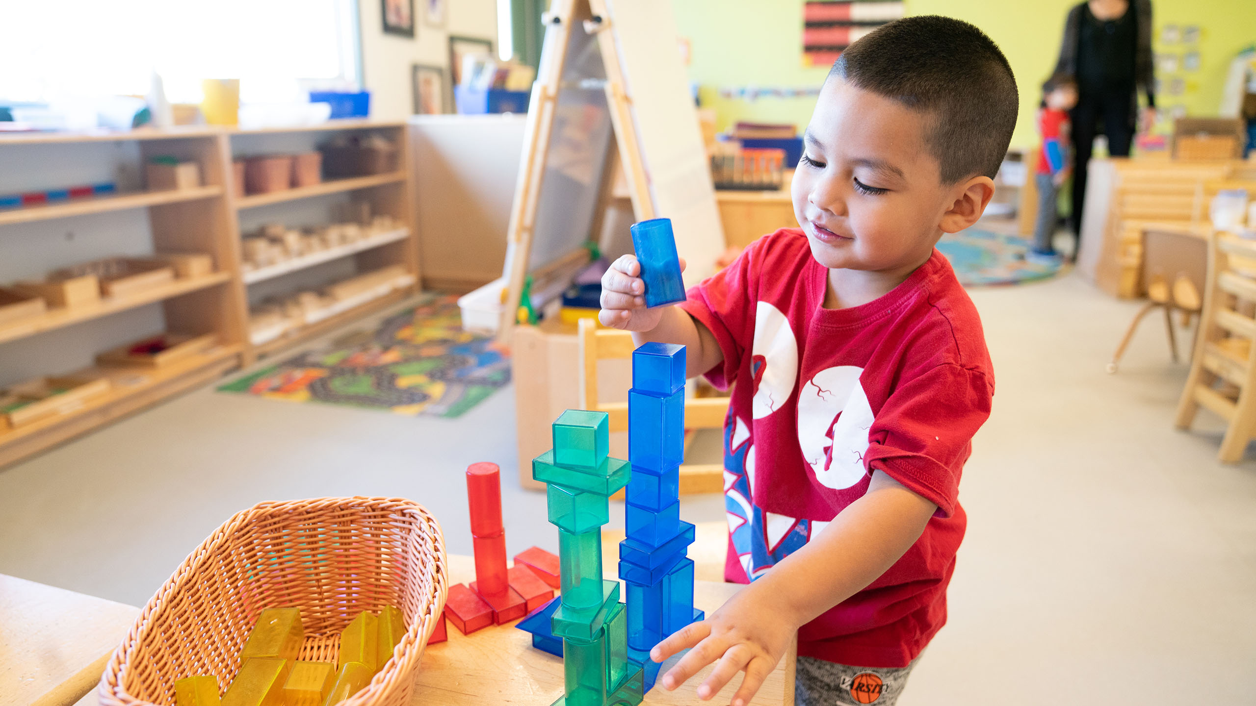 A child gleefully stacks translucent colored blocks