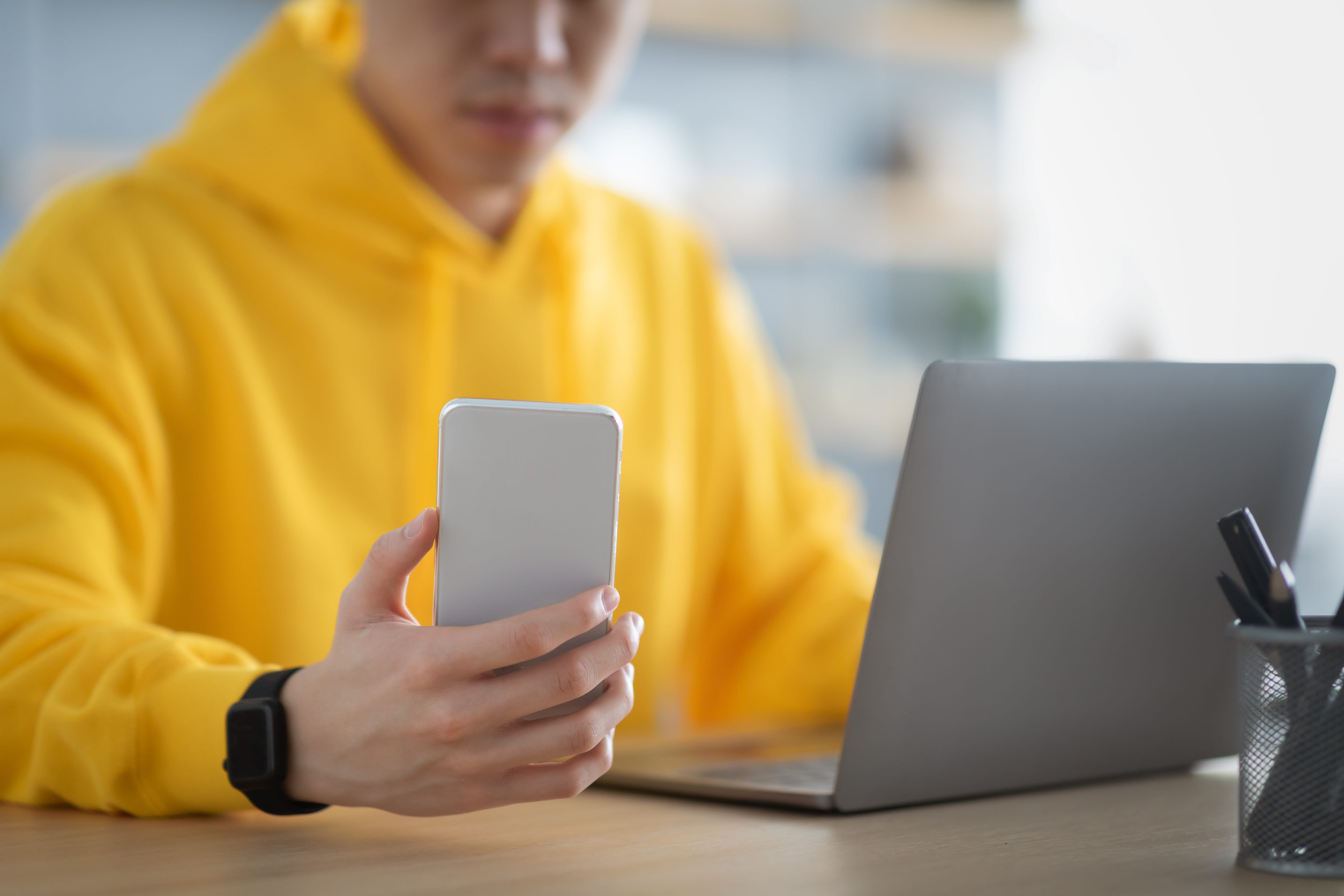 student in yellow sweatshirt who is looking at their smart phone