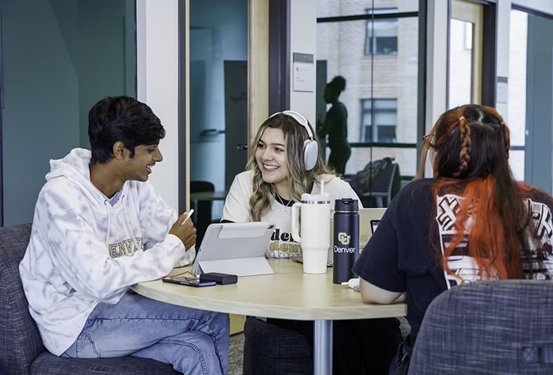 Group of three students working at a table together.