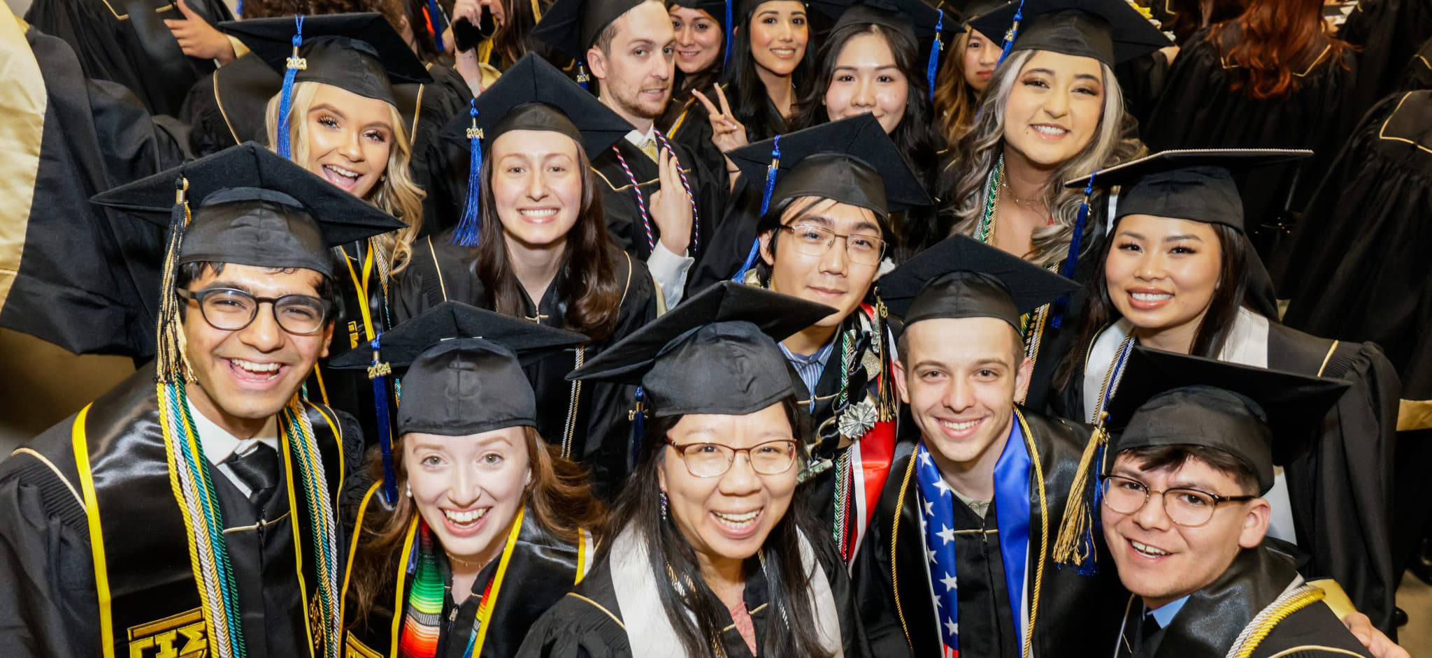 Several CU Denver graduates in commencement regalia smiling in celebration.