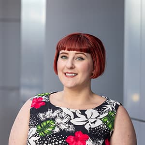 Woman with short red hair smiling with her teeth.