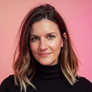 Woman wearing a black sweater with shoulder-length hair and a closed-mouth smile.