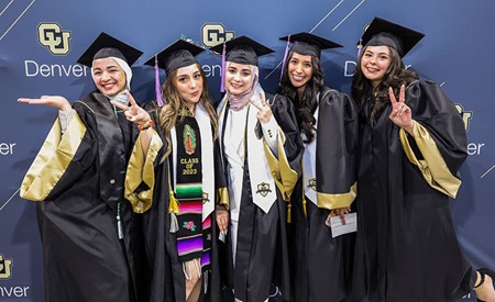 Group of graduates smiling and posing in regalia.