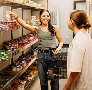 Person shopping at a Food Pantry featuring shelves lined with food.