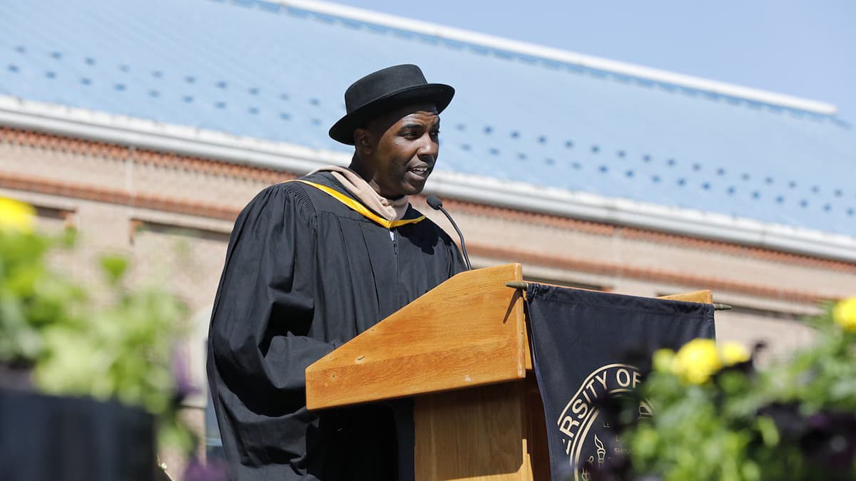 Thomas Detour Evans in CU Denver regalia speaking at a lectern at the Spring 2022 Commencement ceremony.