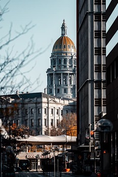 Colorado State Capitol building with focus on the gold dome from a distance from a city street.