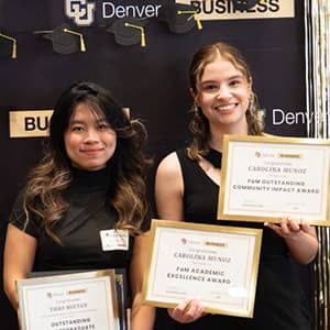 Two students smile while holding up certificates.