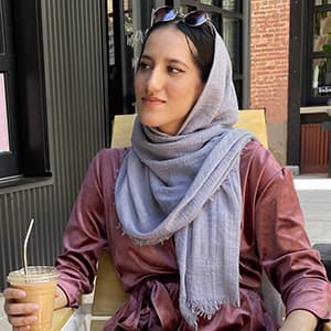 Hussna Yasini at a table drinking coffee