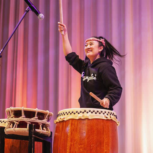 Courtney Ozaki playing a large drum.