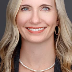 Woman with long blonde hair smiles with her teeth.