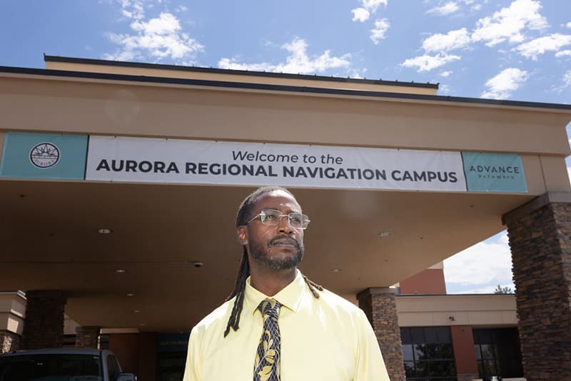 A person stands in front of a building with a sign reading 