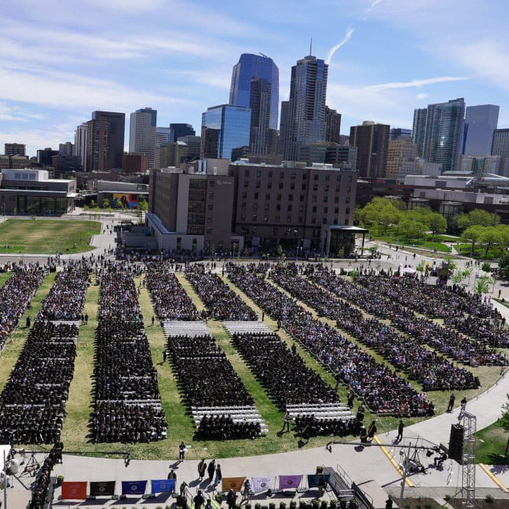 Ariel view of Spring 2022 commencement with city skyline in background.