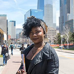 Tatiana Gomes holding books with Downtown Denver city behind her