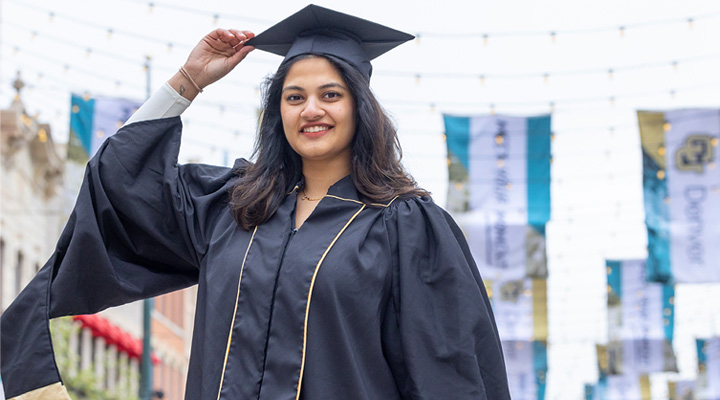CU Denver graduate wearing regalia posing for images in Larimer Square
