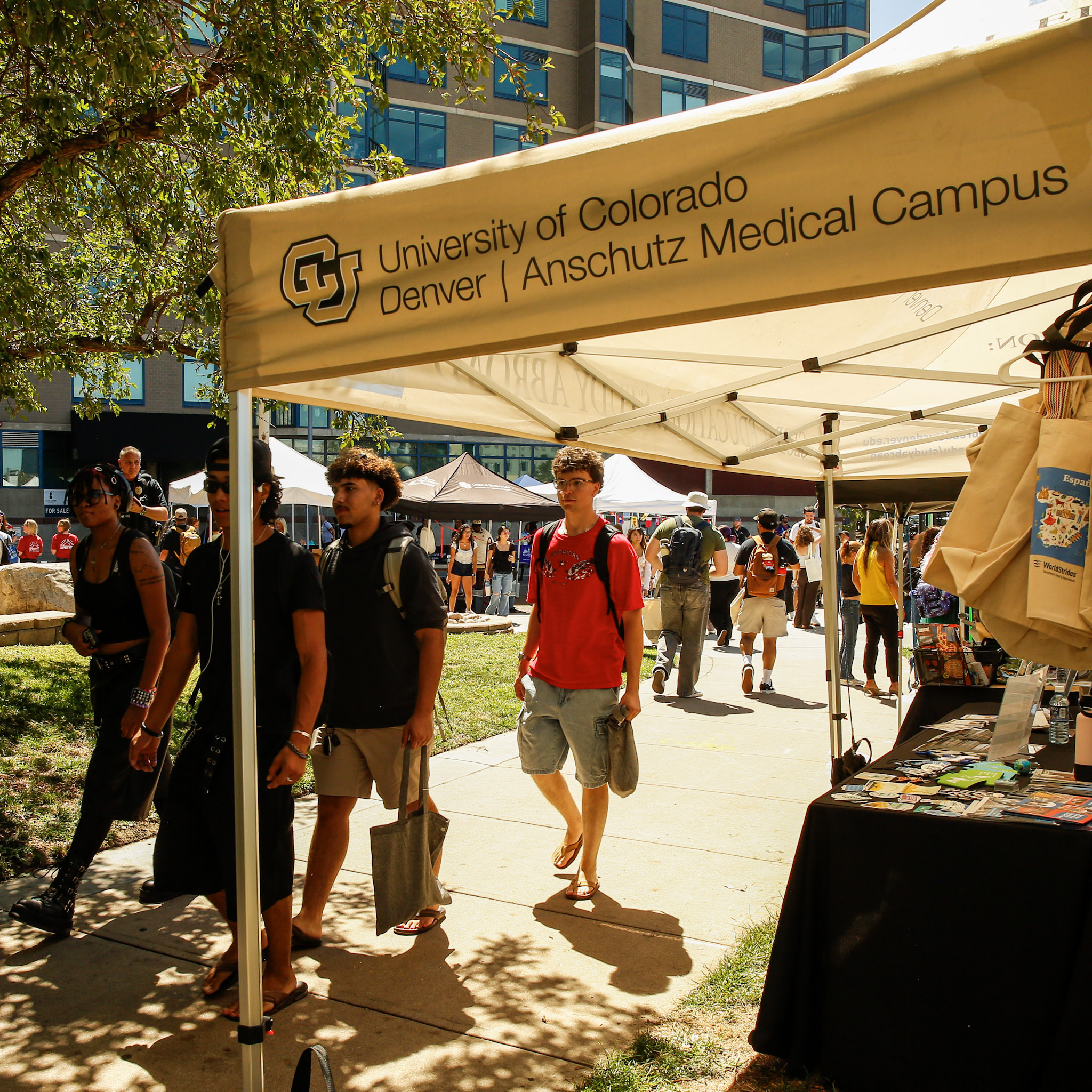 People gather at a block party in front of the Lawrence Street Center, with multiple tents and tables for community organizations and vendors.