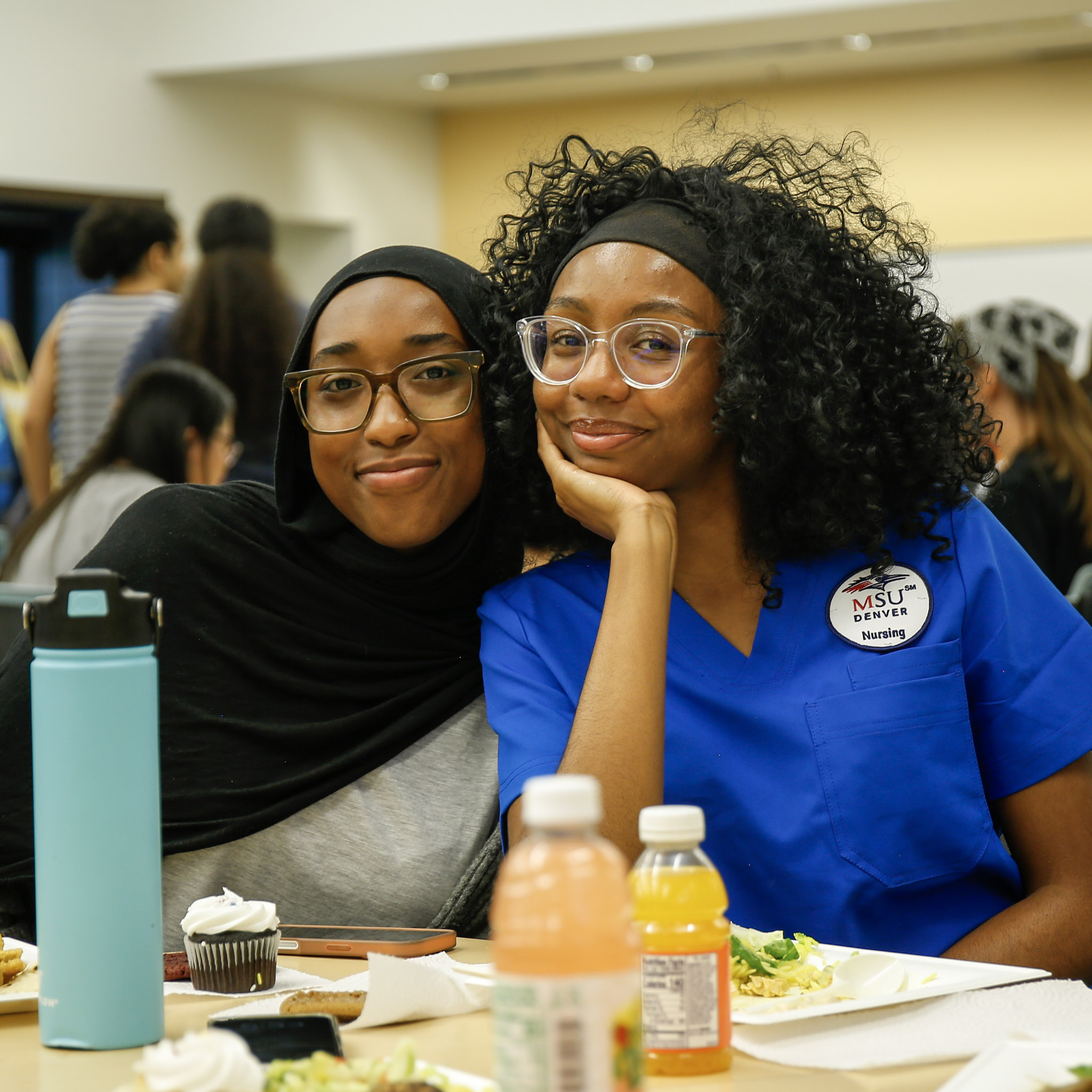 Two friends smiling for a photo while hanging out together at the STEM Open House social event.