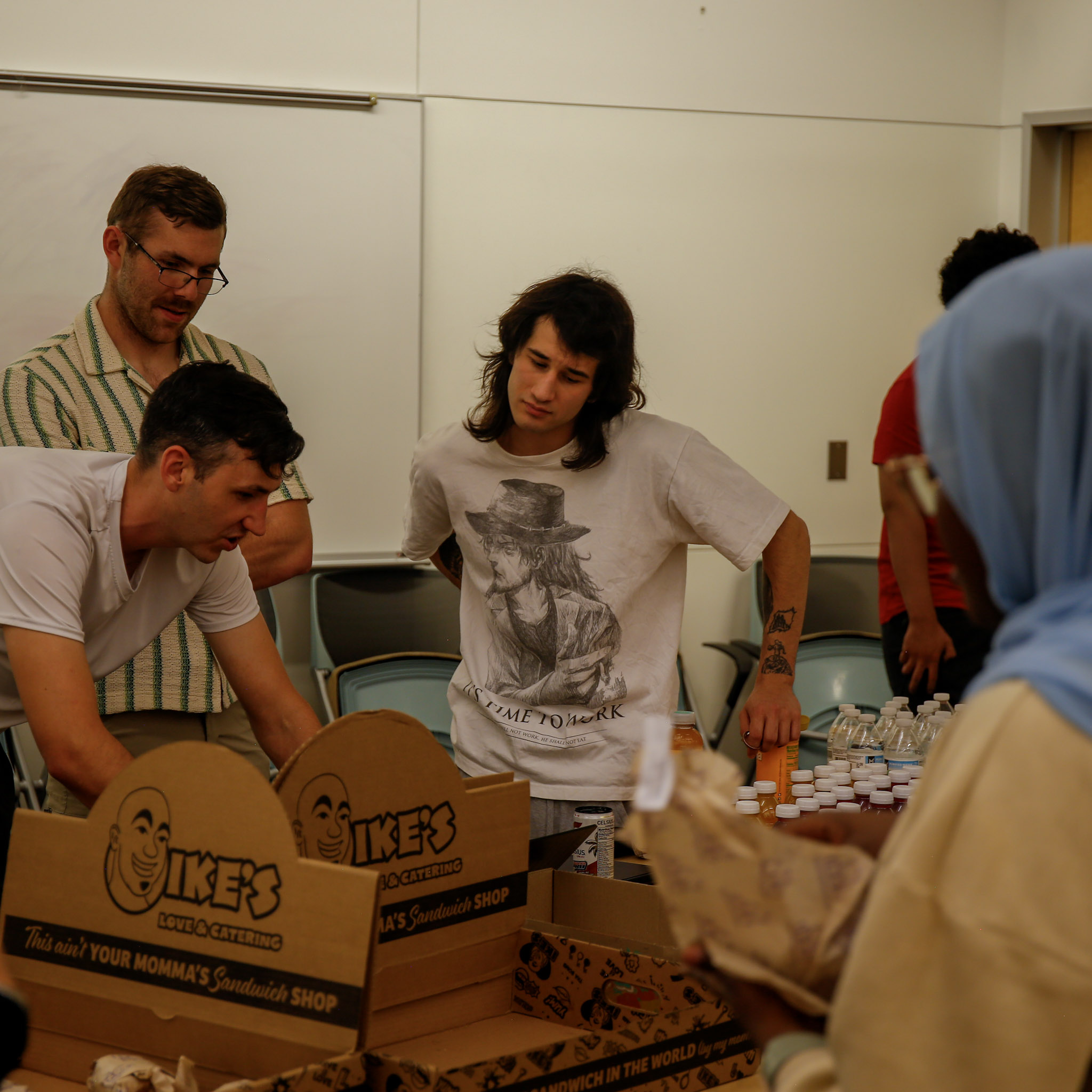 Some competitors gather around a table, working together to start the AI4Infrastructure challenge, while others grab food and drinks.