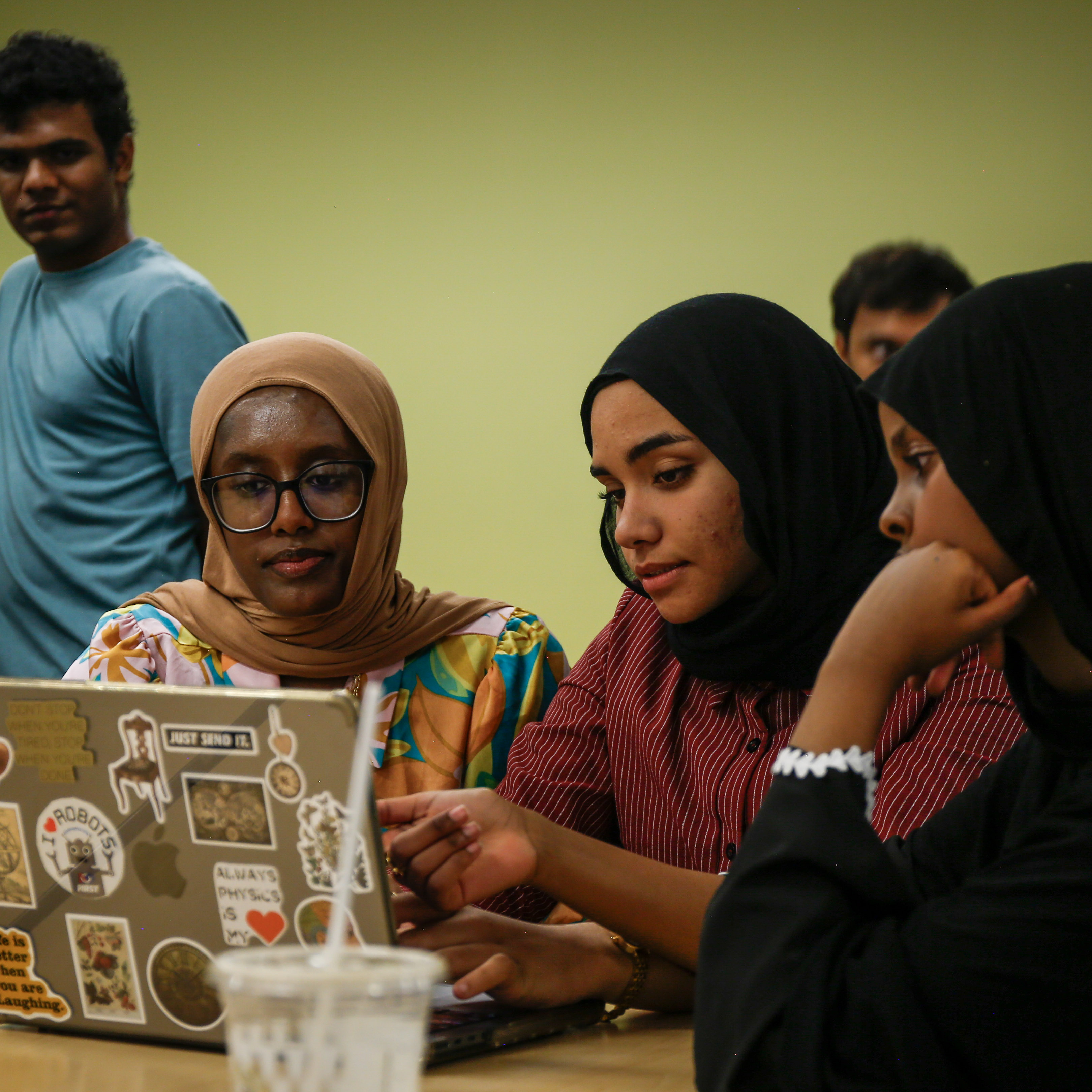 Three women collaborate around a laptop while working on their demo for the AI4Infrastructures Challenge Demo Day.