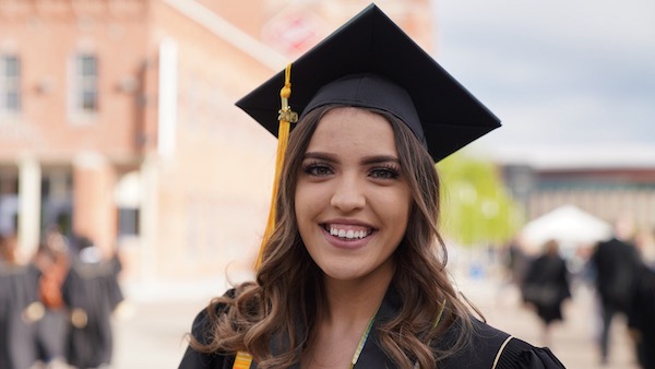 CU Denver student outside in cap and gown