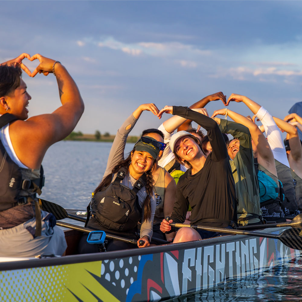 Group of students on boat making heart with arms