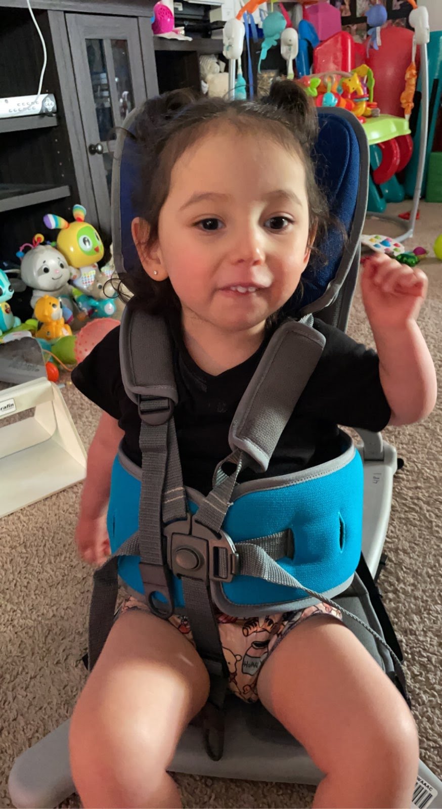 A child strapped into an adapted seat, sitting on the floor