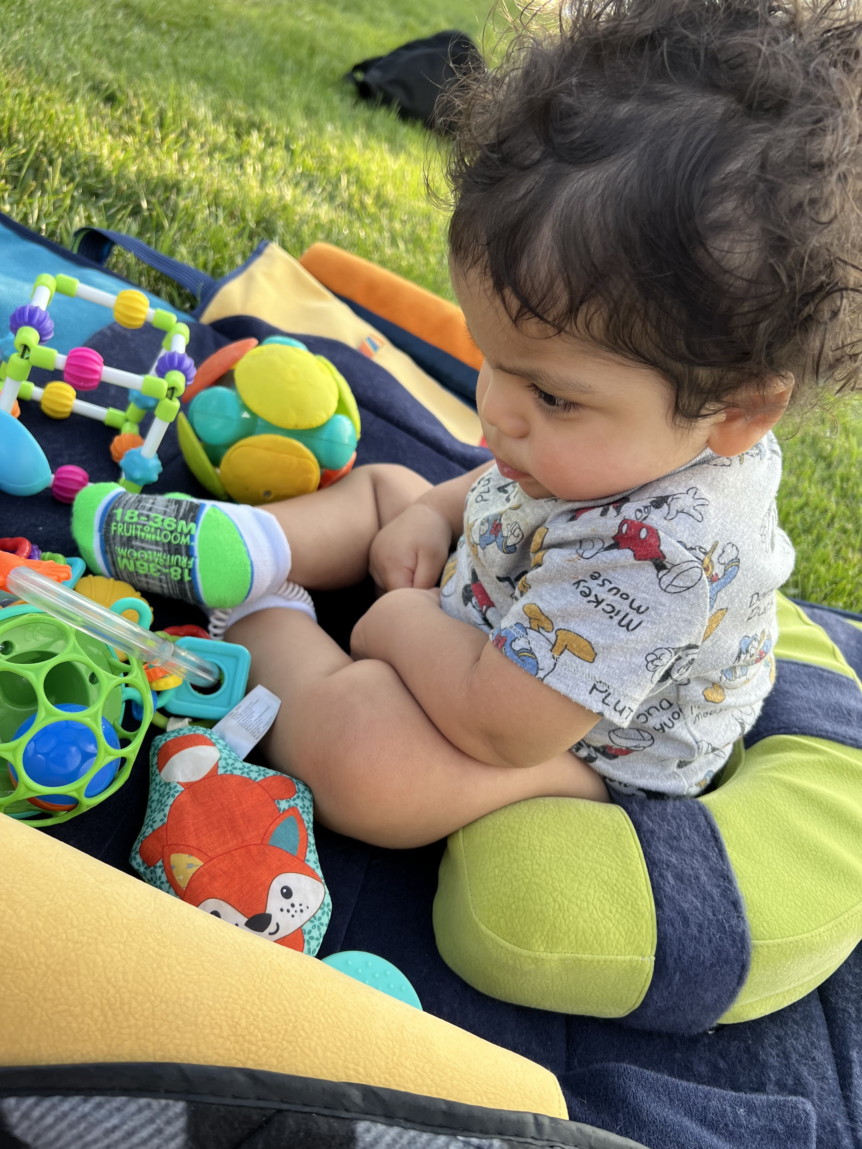 a child sitting on a leckey playpak surrounded by sensory toys