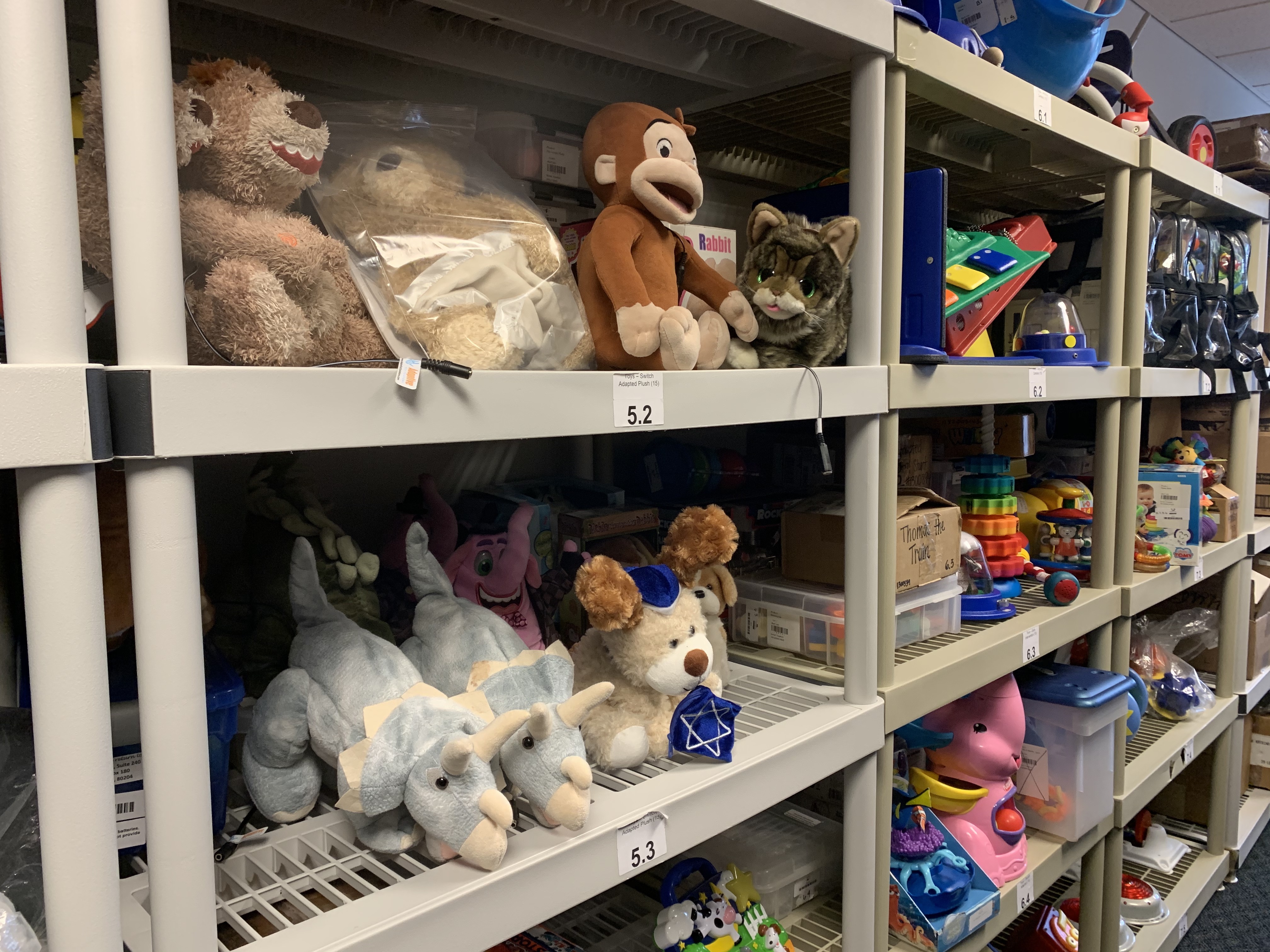A few shelves of toys in the tech for tykes loan library, with stuffed toys at the forefront.