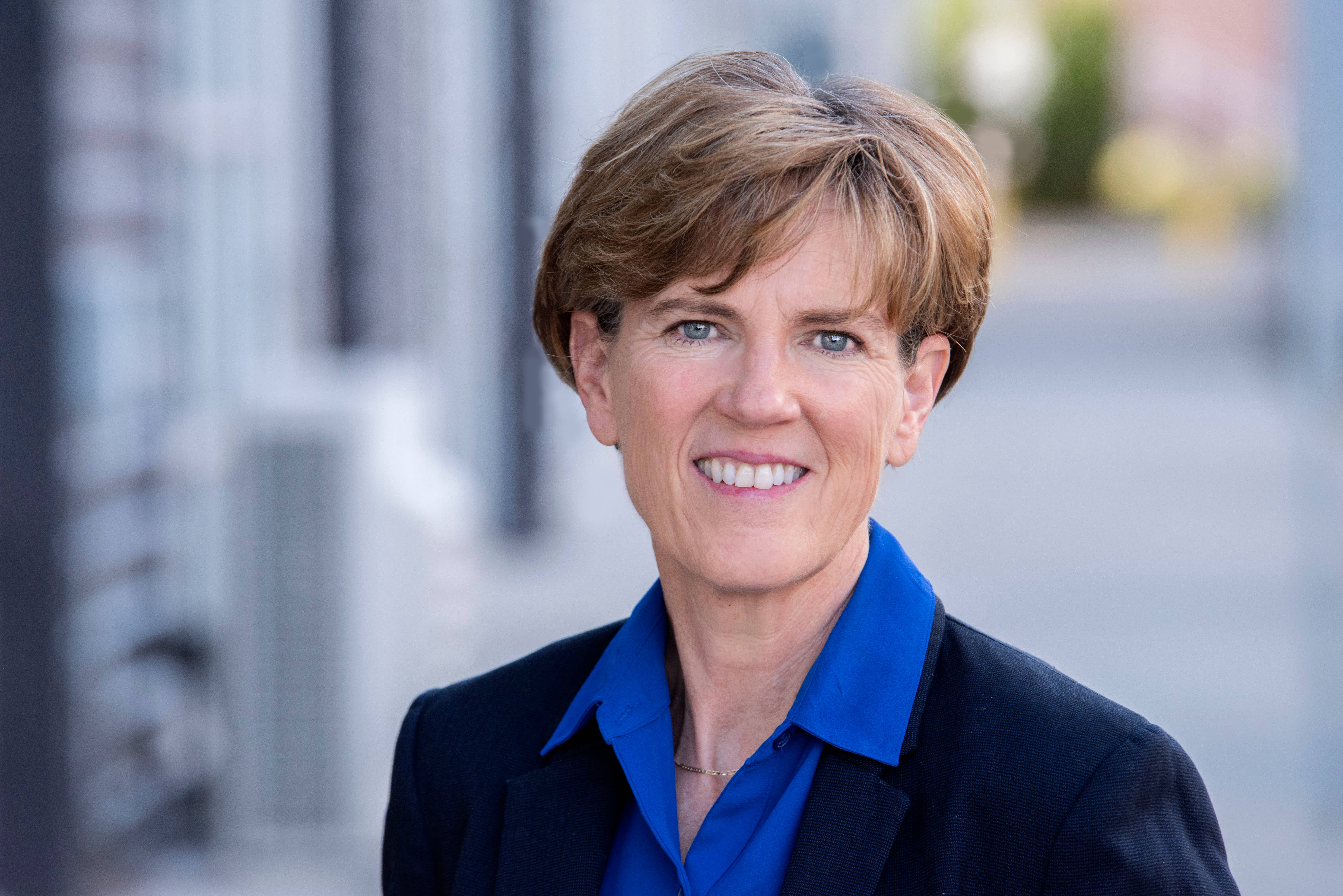 An older woman in professional attire smiling at the camera