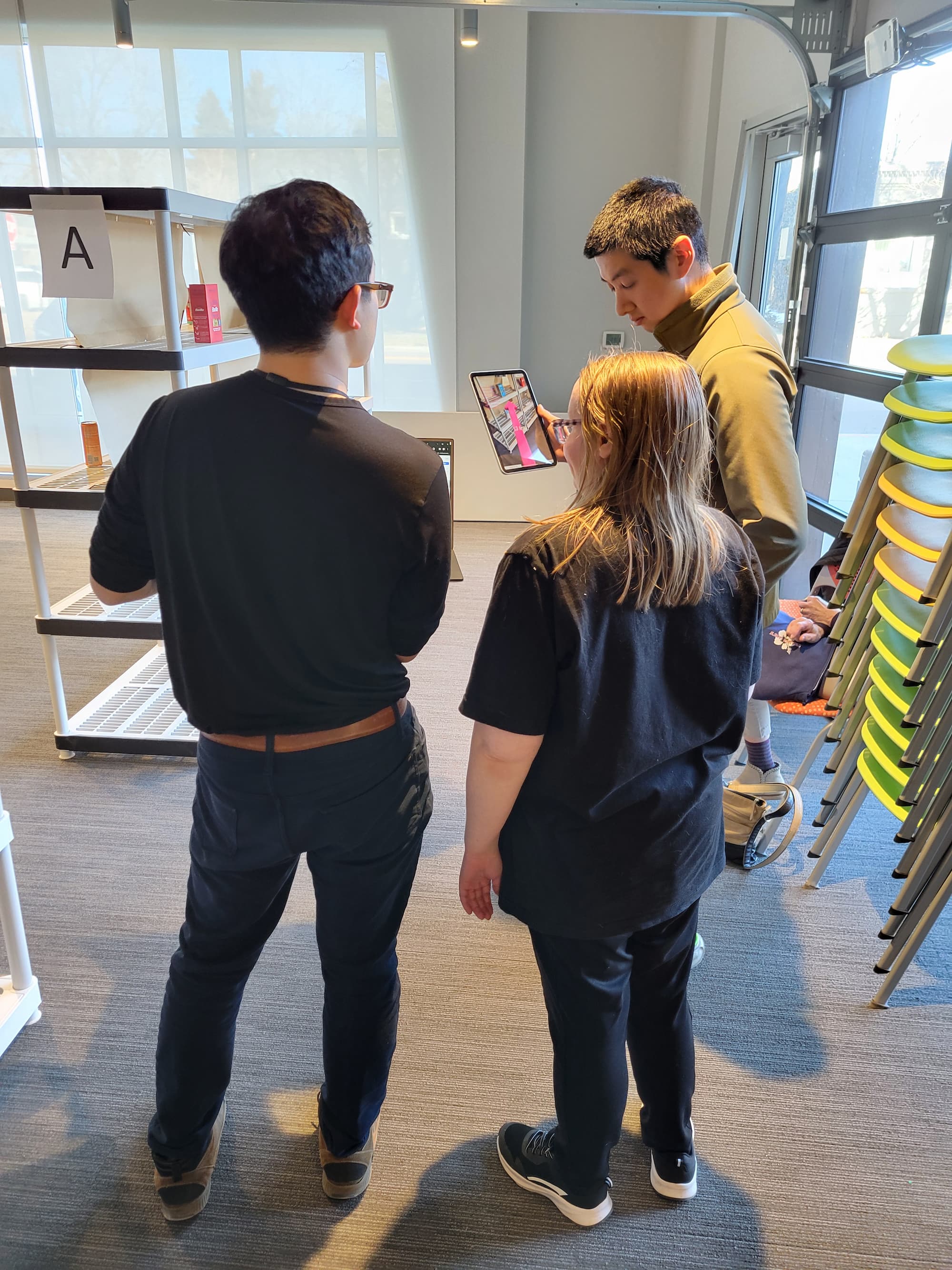 Researcher assists a participant with an intellectual disability in testing the PinPoint augmented reality app on an iPad in a mock store setting.