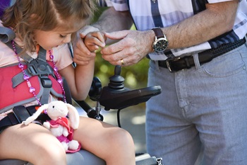 a young child with a disability holds her therapist's hand