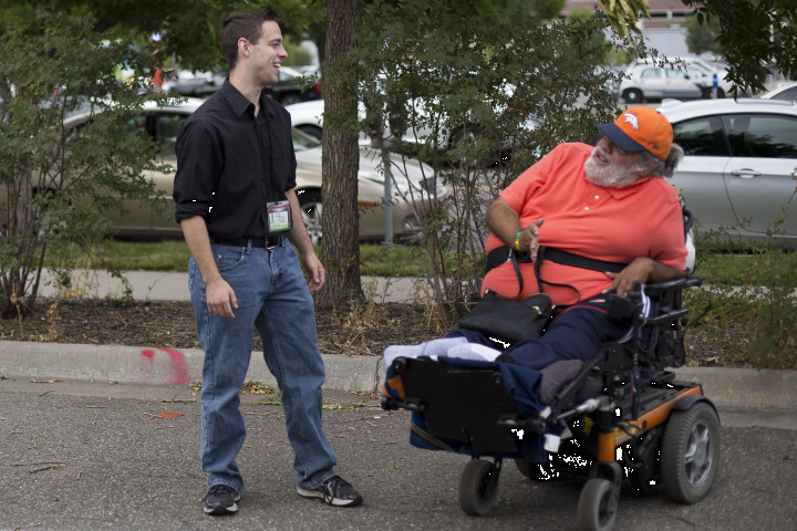 Student smiling and interacting with a gentleman using a wheelchair.