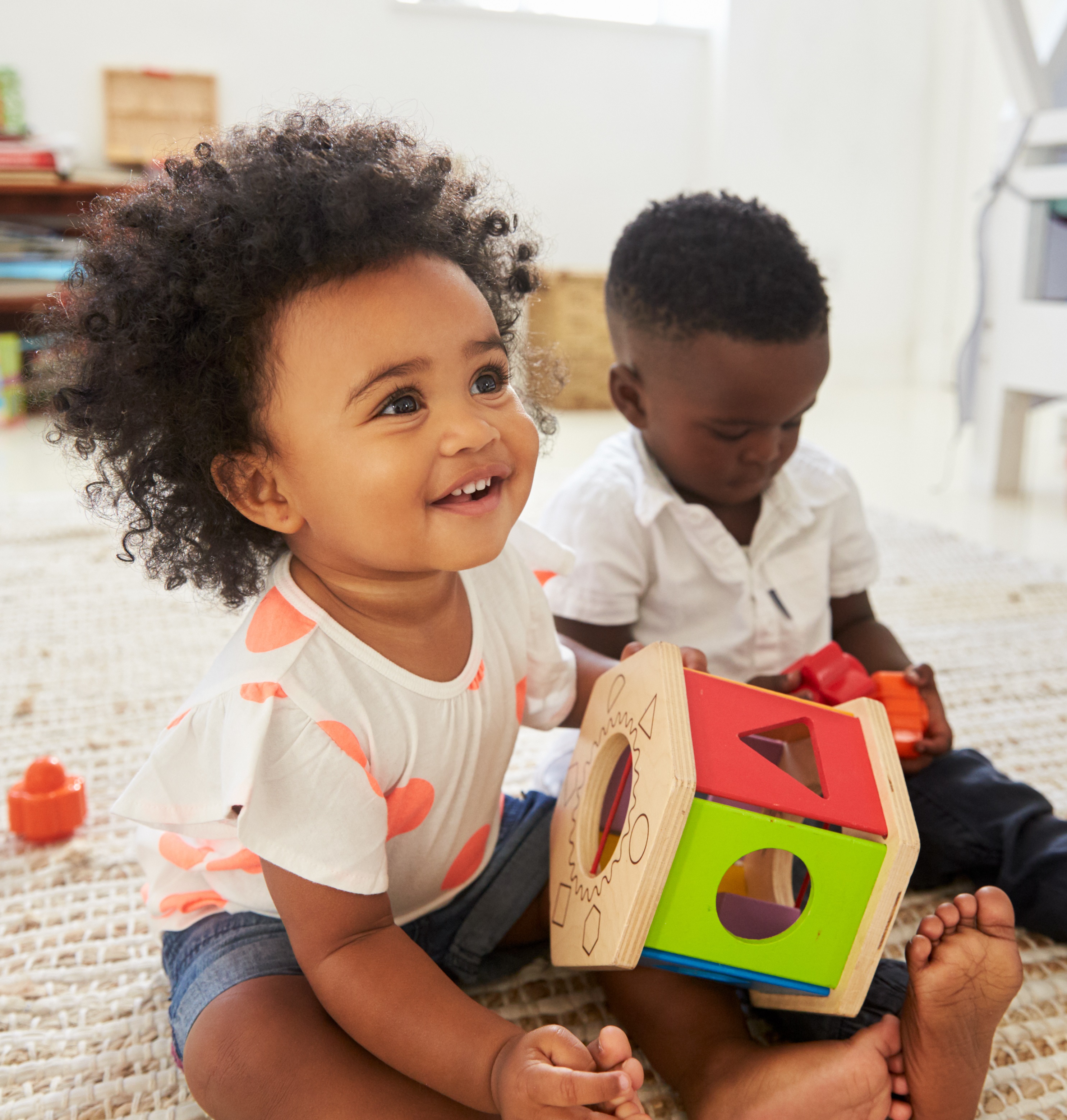 two children sitting on the floor playing with toys