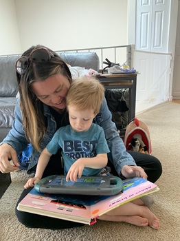 child and SLP sitting with AAC device