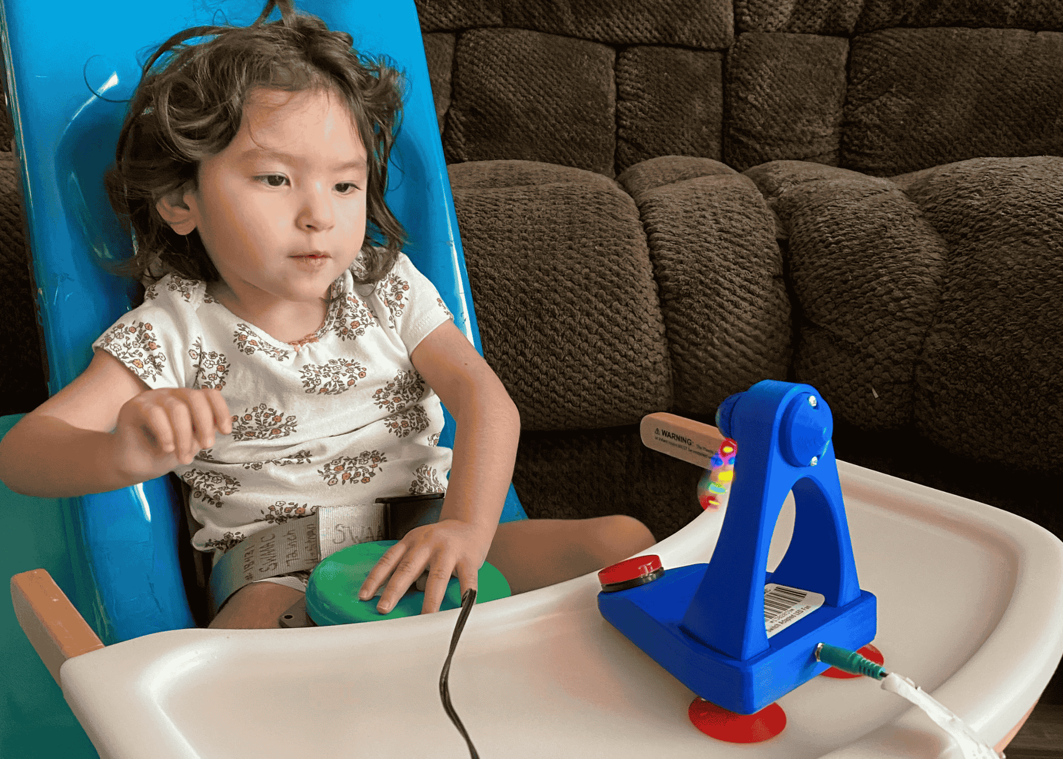 A child sits in a chair interacting with an adaptive toy
