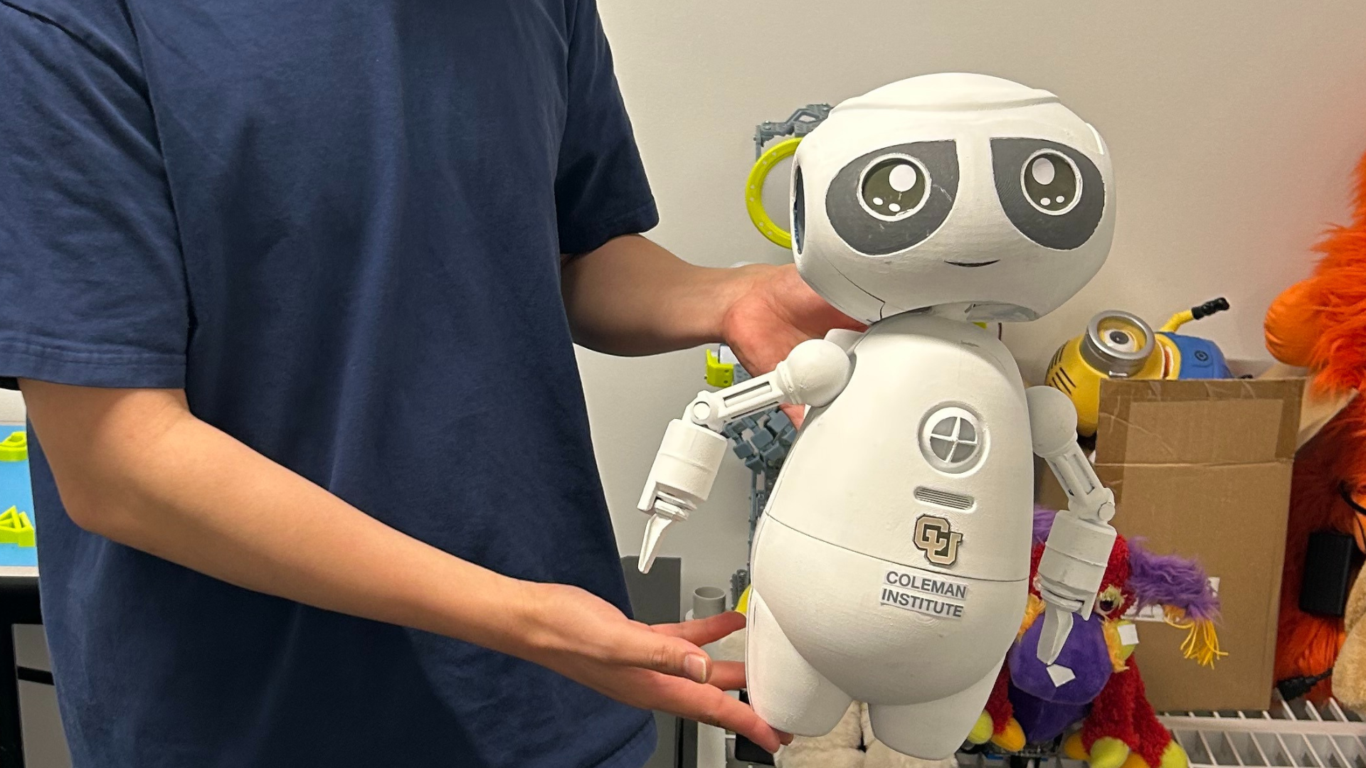 A researcher holds a cute white robot. SMILE-i. Social Multimodal Interface for Learning and Embodied Intelligence.
