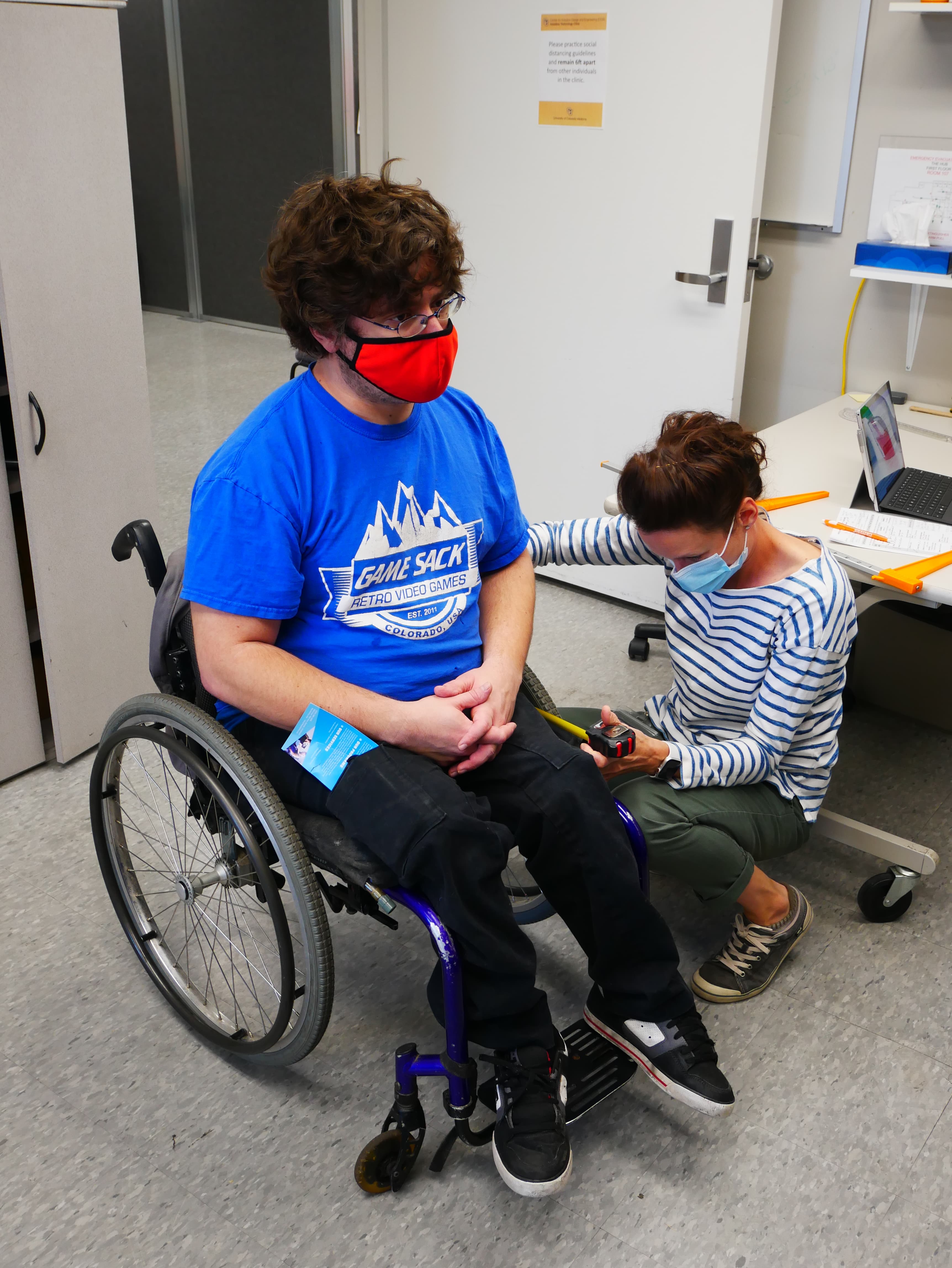 A clinician measures a man in a wheelchair