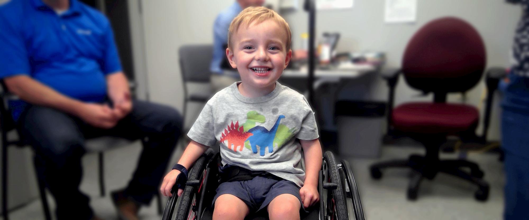 a child smiles while sitting in his wheelchair