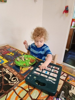 gotalk9 a child eating at a table and pressing on a gotalk9