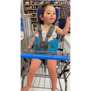a girl sitting in a gotos support seat in a shopping cart