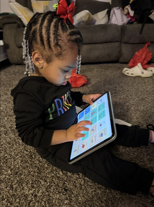 ipadaac2 a child sitting on the floor using an aac device