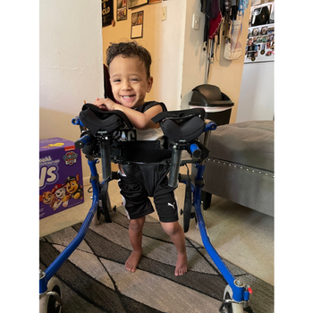 a boy using a gait trainer and smiling