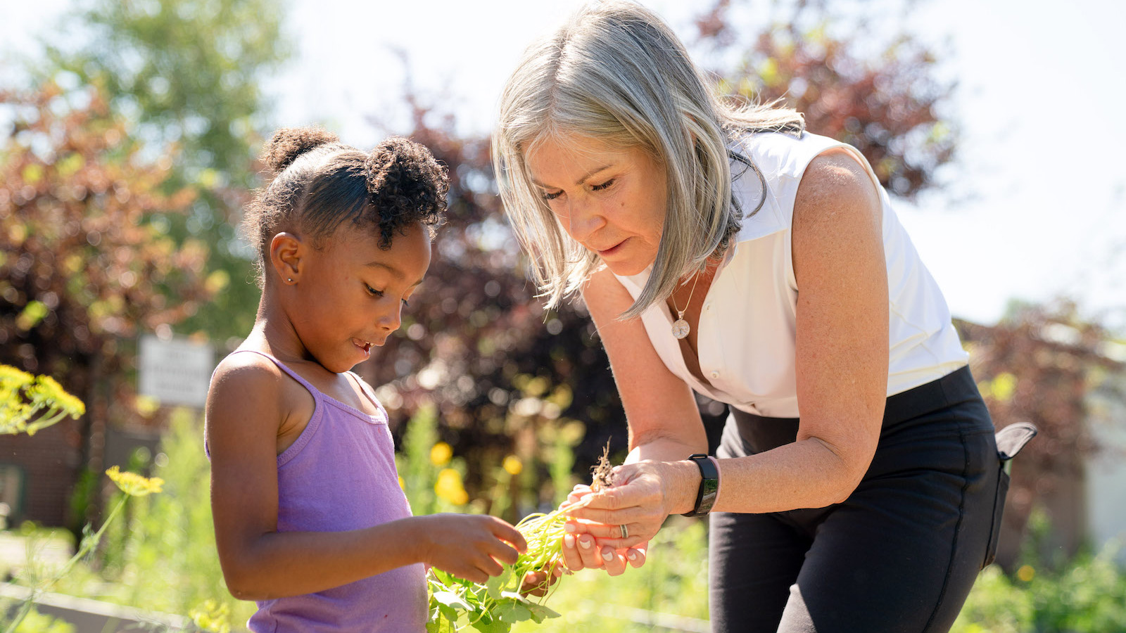 Lori Ryan, of the SEHD, works with a child at Clayton Early Learning's garden.
