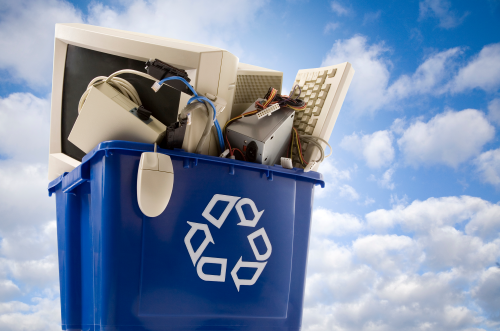 Image of a blue recycle bin with old computer equipment in it.